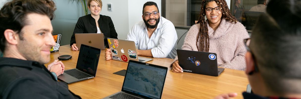 Uma foto com várias pessoas reunidas em uma mesa representando o time da OptimusTech